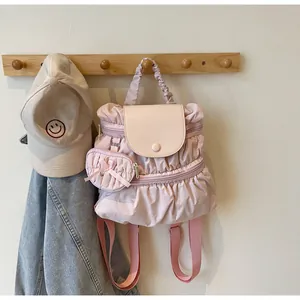 Detailed close-up of pink pleated nylon backpack with mini coin purse and satin bow detail