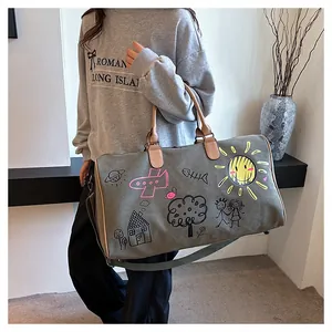 Détail du sac de voyage en toile grise avec graffitis et poignées en cuir chic