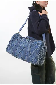 Détail du sac de voyage en denim bleu avec patchwork matelassé et texture à bords effilochés