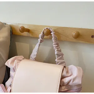 Detail of pink pleated nylon backpack showing scrunchie handle and leather flap detail