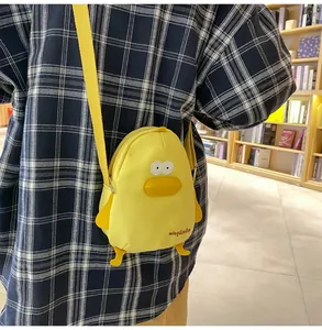 Close-up of yellow canvas duck crossbody bag worn over a blue plaid shirt