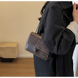 Side view of a vintage brown leather crossbody bag with silver chain and metal lock