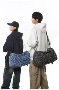 Vue détaillée de grands sacs de voyage en denim matelassé avec bords effilochés et sangle