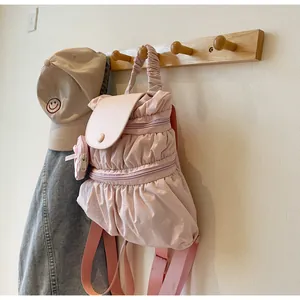 Detailed view of a pink nylon backpack with gathered pleats and a matching mini coin purse