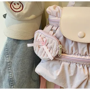 Close-up of pink ruched nylon backpack with a decorative bow pouch and synthetic leather lid
