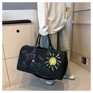 Détail du sac de voyage en toile noire avec imprimés graffiti colorés et anses en cuir