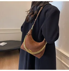 Brown suede hobo bag with gold chain strap worn by model in black wool coat