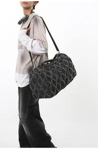 Détail du sac de voyage en denim matelassé noir avec bords effilochés et bandoulière