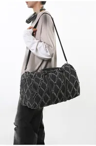 Détail du sac de voyage en denim matelassé montrant les bords effilochés et le motif rhomboïde