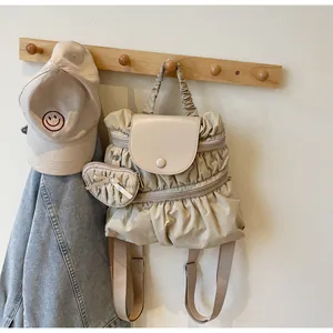 Detail of pleated beige nylon backpack with heart-shaped charm and magnetic snap closure