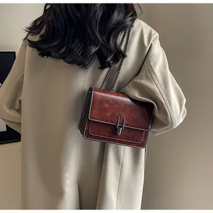 Retro dark brown leather crossbody bag with chain strap shown on person profile