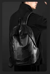 Detail of black PU leather backpack showing geometric patchwork textures and premium stitching