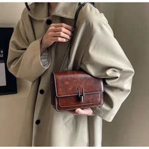 Detail of vintage brown crossbody bag featuring contrast stitching and metallic chain strap