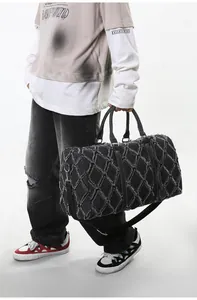 Détail du sac de voyage en denim noir matelassé avec bords effilochés et bandoulière réglable