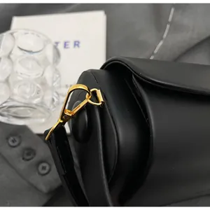 Detail of premium black leather crossbody bag with polished gold metal hardware hook