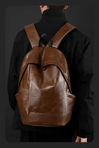 Detailed view of the brown PU leather patchwork texture and stitching on the men's backpack