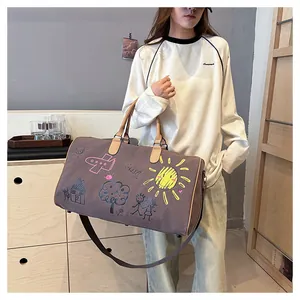 Détail du sac de voyage en toile avec graffitis colorés et poignées en cuir