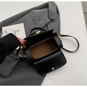 Detail view of black PU leather handbag with gold metal lock and striped interior lining