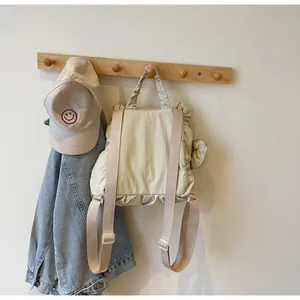Detail of beige pleated nylon backpack with soft ruffles hanging on a wooden hook