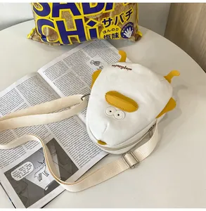 Detail view of white canvas fish-shaped crossbody bag with yellow felt fins and big eye embroidery