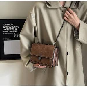 Detail of vintage brown leather crossbody bag with metal buckles and chain strap