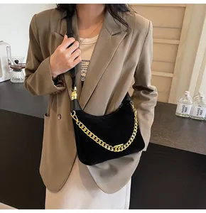 Detailed close-up of a black faux suede hobo bag with thick gold chain and leather strap