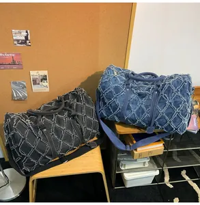 Détail du tissu à losanges effiloché sur les sacs de voyage noirs et bleus à grande capacité