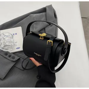 Detailed shot of black matte leather shoulder bag with gold shell clasp and brand text
