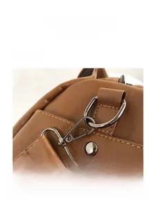Détail du crochet en métal gris foncé amovible sur un sac en cuir marron à grain litchi