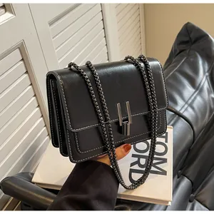 Detail view of black glossy flap bag with white contrast stitching and chain strap