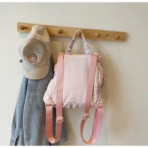 Detail view of pink nylon backpack featuring adjustable straps and ruched top handle