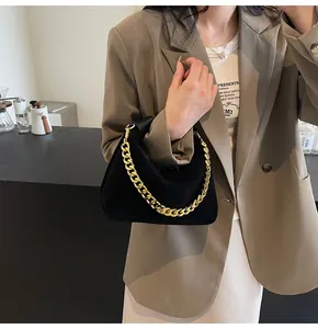 Detailed view of black suede half-moon bag featuring thick gold metal chain handle