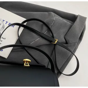 Detail of adjustable leather strap and elegant golden shell lock on black handbag