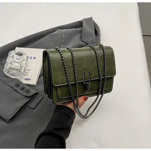 Detail of vintage green crossbody bag featuring cracked leather texture and chain strap