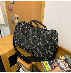 Détail du sac de voyage en denim matelassé noir avec bords effilochés sur bois