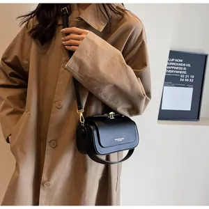 Detail of minimalist black leather crossbody bag with white fashion text and gold hardware