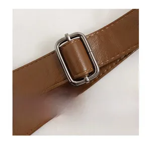 Détail de la boucle en métal réglable et de la sangle en cuir synthétique brun avec coutures