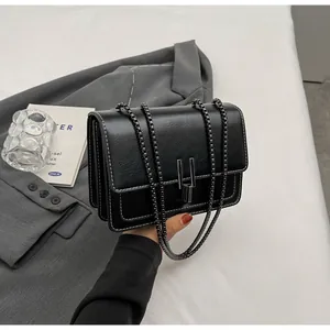 Detail of black crossbody bag with white contrast stitching and dark metal U-buckle