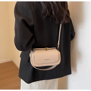 Detail view of stylish apricot crossbody flap bag with golden buckle on female model
