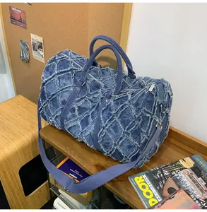 Détail du sac de voyage en denim matelassé bleu avec bords effilochés et fermeture