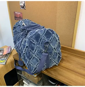 Détail du sac de voyage en denim bleu avec motif à franges sur un banc en bois