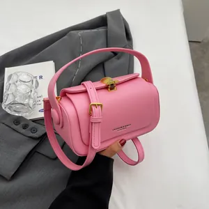 Pink matte leather handbag with gold shell clasp and adjustable strap on a suit