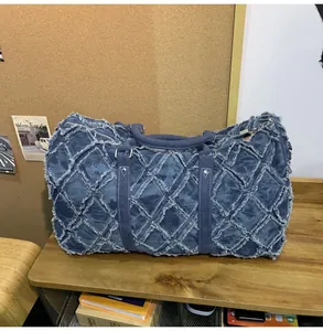 Détail macro du sac de voyage en jean matelassé avec franges usées et coutures rétro