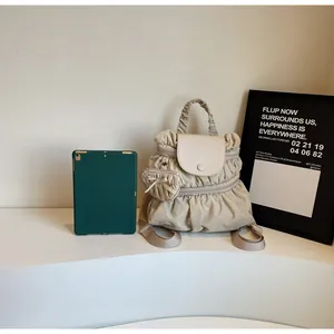 Detail view of apricot pleated nylon backpack with matching heart shaped charm on the side