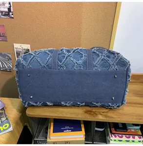 Détail du sac de voyage en denim avec motif matelassé et pieds de protection en métal