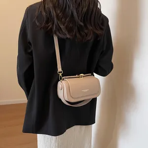 Fashionable beige leather crossbody flap bag with gold hardware worn on black blazer