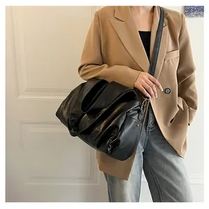 Gros plan d'un grand sac cabas en cuir souple noir porté avec boucles argentées