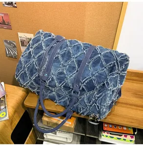Détail du sac de voyage en denim bleu avec motif à losanges et bords effilochés stylés