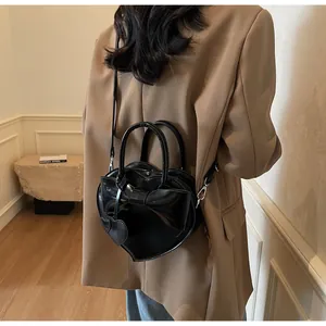Vista modella di borsa nera a forma di cuore con grande fiocco e tracolla regolabile