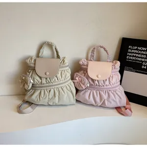 Detailed view of ruched nylon backpacks in cream and pink with matching mini pouches